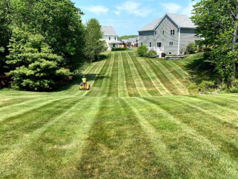 gray home with professional on riding lawn mower cutting lawn