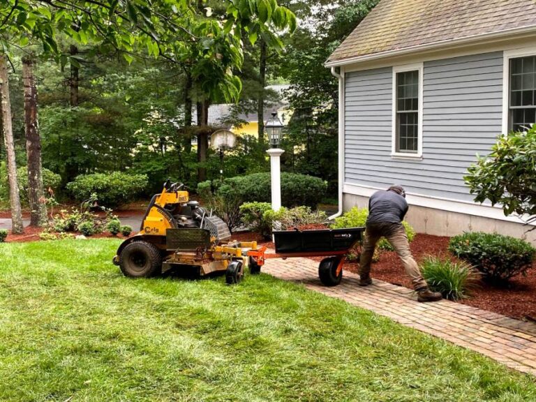professional installing mulch next to yellow machinery