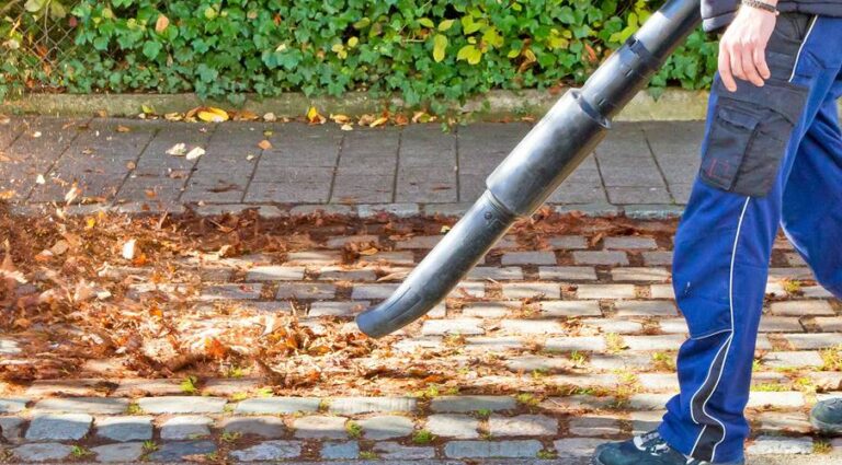 a man using a leaf blower to clean up leaves and debris from a property. Maione Landscapes offers property cleanup services